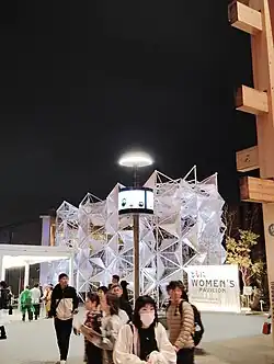 Visitors in front of a building with a white façade with triangular panels