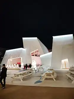 White building with angular walls and a Canada sign in front of it
