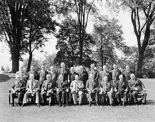A posed group of men, taken out of doors, with one row seated, one standing
