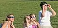 Amateur scientists observing eclipse in ألباكركي. They are using colored filtered glasses for safe viewing provided by the Department of Physics and Astronomy at The University of New Mexico.