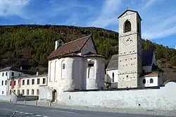 A clock tower standing beside two small houses and a museum