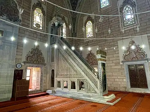 منبر الجامع ونوافذ الإضاءة العلوية ونافذة سفلية وأحد أبواب الجامع الخشبية.