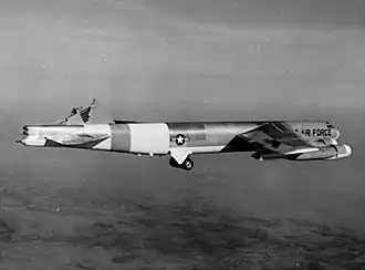 Black-and-white photo of a B-52 inflight with its vertical stabilizer sheared off