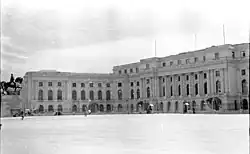 Large public building fronted by sentry boxes and a near-empty square.
