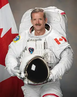 Photo of Neil Armstrong, posing in a space suit with the helmet off.