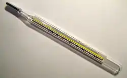 An analog ميزان حرارة طبي showing a temperature of 38.7&nbsp;°م or 101.7&nbsp;°ف