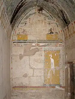 معبد حتشبسوت الجنائزي: بنات آوى مستلقية (الثلث العلوي) فوق الهيروغليفية للسماء ("حيوان أليف") و الشمس المجنحة، أسفل إميوت