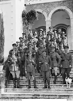 Soldiers in cavalry uniform on steps outdoors, with canine mascot