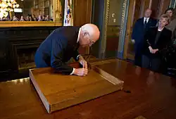 Dick Cheney signing the inside of a desk drawer.