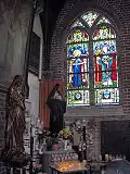 كنيسة صغيرة في الجزء الخلفي من كنيسة Onze-Lieve-Vrouw-ter-Duinenkerk. أوستند، بلجيكا. موضح على الزجاج المعشق صورتي القديسة جودليف والقديس إيدسبالد.