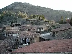 Old houses with red roofs, a hill in the background.