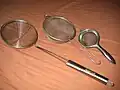 Several wire meshes shaped like bowls, with metal handles.