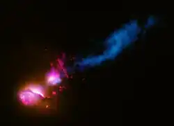 A brilliant red galaxy on the left interacts with a blue galaxy on the right, forming the merging active galaxy pair 3C 321.