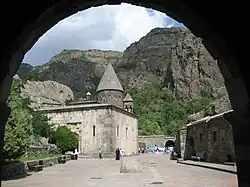 View at a church with cliffs in the background through an arch
