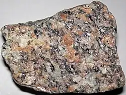 The polished face of a granite slab showing an even pattern of white, greenish and black crystals.