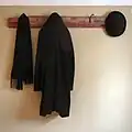 شماعة على الحائط معلق عليها معطف وقبعة ووشاح