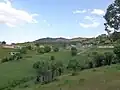 قرية محاطة بالخضرة الكثيفة كما تُرى من التل