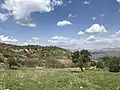 قرية كوفلي وسط التلال الخضراء والجبال البعيدة