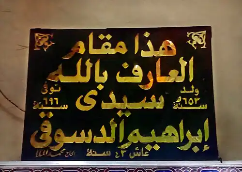 لافتة مهداة إلى المسجد الإبراهيمي موضوعة على يمين أبواب غرفة الضريح مكتوب عليها تاريخ ميلاد الدسوقي وتاريخ وفاته.