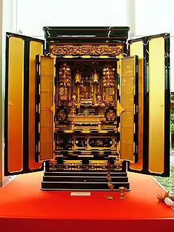 An ornate butsudan with open doors displaying an enshrined Amida Buddha. A Butsudan in the Jodo Shinshu Buddhism tradition.