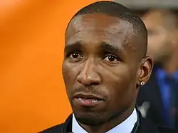 A black man with very short hair and a diamond earring in his left ear