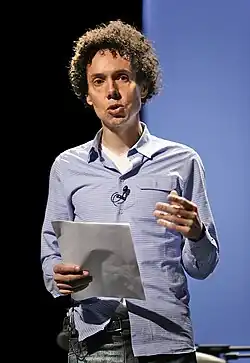 A man holds a piece of paper and is giving a speech