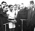 بطل رفع الإثقال الفلسطيني عيسى الطمس في لقطة يتسلم فيها الكأس من الرئيس العام لحراسة الأراضي المقدسة 1953