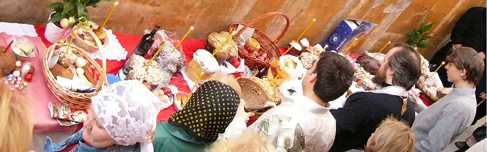 كاهن كنيسة روما الأرثوذكسية (الثاني من اليمين) يبارك أطعمة الفصح بضمنها خبز الكوليتش.