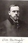 A middle-aged bearded man in a smart dress.