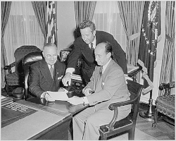 Three men at a desk reviewing a document