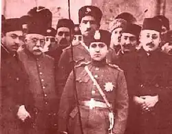 رضا بهلوي يقف خلف شاه أيران السابق أحمد ميرزا القاجاري الذي قام بخلعه عام 1925 م