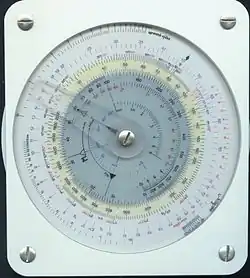 تُظهر الصورة وجهًا من أوجه حاسبة الطيران العسكرية الدائرية TMP-7 تُستخدم في الملاحة الجوية، وهي أداة دقيقة تعتمد على مقياس دائري متحرك لتسهيل حسابات الوقت، السرعة، المسافة، واستهلاك الوقود. تحتوي على عدة دوائر متداخلة مرقّمة بعناية، وتُمكن الطيار من إجراء العمليات الحسابية بسرعة وبدقة أثناء الطيران دون الحاجة إلى آلة حاسبة إلكترونية. تُستخدم هذه الحاسبة في البيئات العسكرية لما توفره من دقة، وتُعرف بين الطيارين بأداة لا غنى عنها في مهام الملاحة الجوية المعقدة.