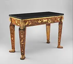 طاولة؛ 1775 - 1780 ؛ سطح من الخشب المنحوت والمطلي والمذهّب جزئيًا ، والجرانيت الأسود ليس أصليًا للطاولة ؛ 89.9 × 123.5 × 58.4 سم ؛ متحف متروبوليتان للفنون (مدينة نيويورك)