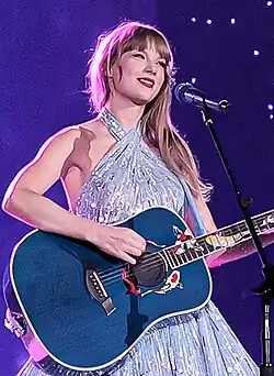 Taylor Swift wearing a black dress singing on a mic