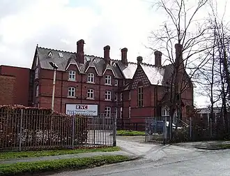 A large brick building with a sign saying "RNC"; a fence and some trees in the foreground.