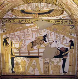 Fresco of a mummy lying on a bier. Women stand at the head and foot of the bier, while a winged woman kneels in the register above