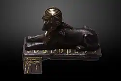 تمثال أبو الهول البرونزي لتحتمس الثالث فوق تسعة أقواس؛ وتظهر أيضًا عمود جد دومينيون على جانب القاعدة.
