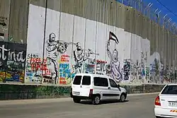 جدارية تُمثل جنديين إسرائيليين يستهدفان امرأة فلسطينية