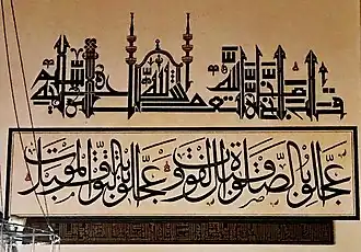 «عجلوا بالصلاة قبل الفوت، وعجلوا بالتوبة قبل الموت»ومكتوب تحتها بالخط الكوفي: ﴿اللَّهُ لَا إِلَٰهَ إِلَّا هُوَ الْحَيُّ الْقَيُّومُ ۚ لَا تَأْخُذُهُ سِنَةٌ وَلَا نَوْمٌ ۚ لَّهُ مَا فِي السَّمَاوَاتِ وَمَا فِي الْأَرْضِ ۗ مَن ذَا الَّذِي يَشْفَعُ عِندَهُ إِلَّا بِإِذْنِهِ ۚ يَعْلَمُ مَا بَيْنَ أَيْدِيهِمْ وَمَا خَلْفَهُمْ ۖ وَلَا يُحِيطُونَ بِشَيْءٍ مِّنْ عِلْمِهِ إِلَّا بِمَا شَاءَ ۚ وَسِعَ كُرْسِيُّهُ السَّمَاوَاتِ وَالْأَرْضَ ۖ وَلَا يَئُودُهُ حِفْظُهُمَا ۚ وَهُوَ الْعَلِيُّ الْعَظِيمُ﴾--(آية الكرسي من سورة البقرة - الآية 255)