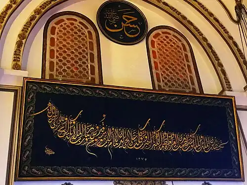 لوحة فنية بالخط العربي معلقة على جدران مسجد أُولو جامع ببورصة،  مكتوب فيها: تحصّنت بذي الملك والملكوت واعتصمت بذي العزة والعظمة والكبرياء والجبروت وتوكلت على الحي الذي لا ينام ولا يموت سبوح قدوس ربنا ورب الملائكة والروح والله ربي لا شريك له 1275 (هجرية)