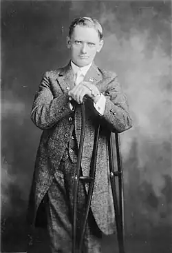 A middle-aged man dressed in a suit leans on crutches