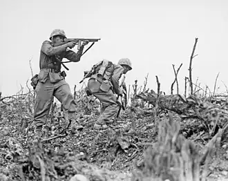 Two Marines from the 2nd Battalion، 1st Marines&nbsp;&nbsp;[لغات أخرى]‏ advance on Wana Ridge on 18 May 1945.